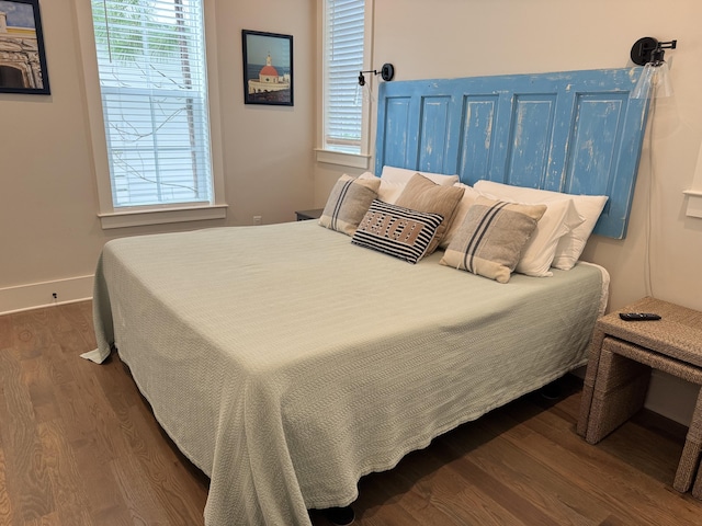 bedroom with baseboards and dark wood-type flooring