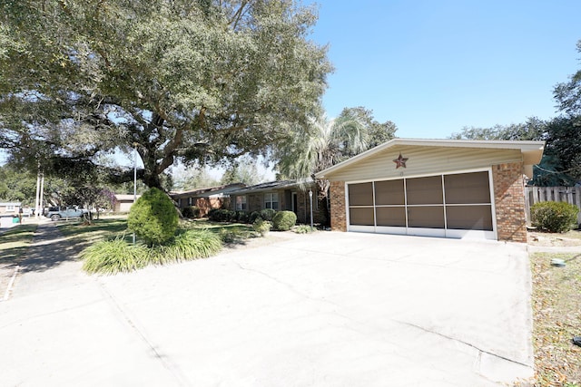 view of front facade featuring a garage, fence, concrete driveway, and brick siding