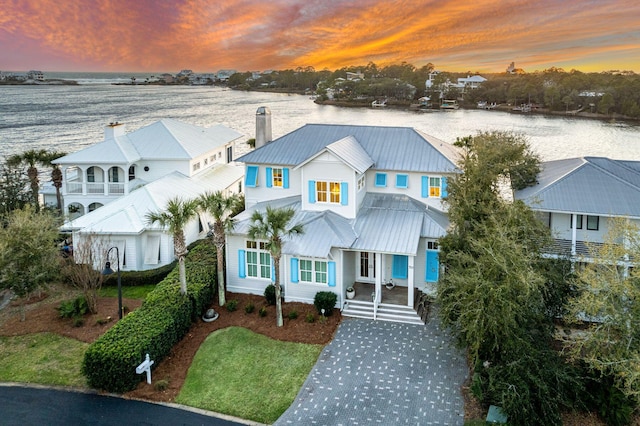 view of front of home with driveway, a chimney, and a water view