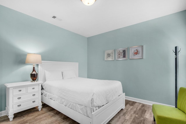 bedroom featuring baseboards, visible vents, and wood finished floors