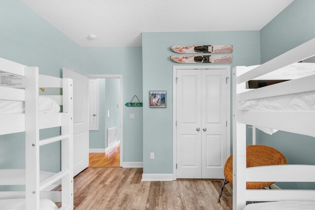 bedroom featuring baseboards, a closet, visible vents, and wood finished floors