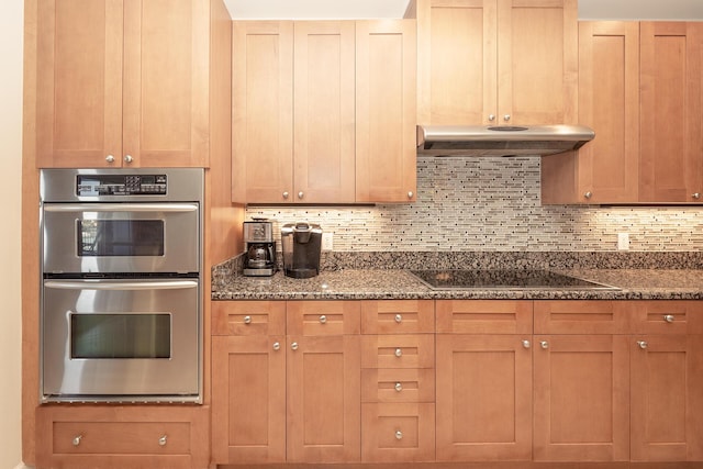 kitchen featuring tasteful backsplash, dark stone countertops, black electric stovetop, under cabinet range hood, and double oven