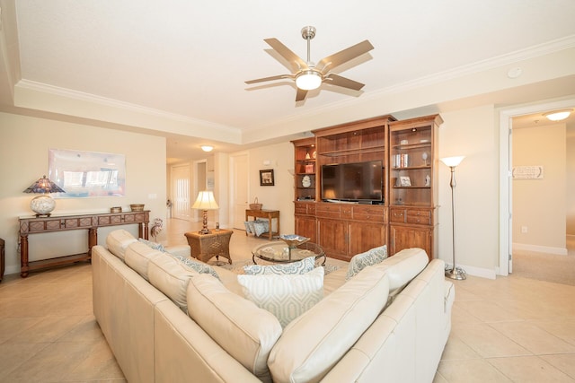 living room with light tile patterned flooring, a ceiling fan, baseboards, a tray ceiling, and crown molding