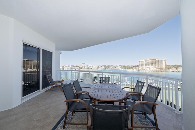 balcony featuring a view of city, outdoor dining area, and a water view