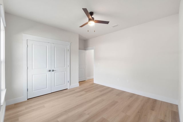 unfurnished bedroom with a ceiling fan, light wood-style flooring, baseboards, and a closet