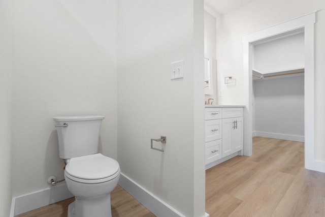 bathroom with vanity, wood finished floors, toilet, and baseboards