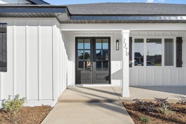 property entrance with board and batten siding, french doors, and roof with shingles