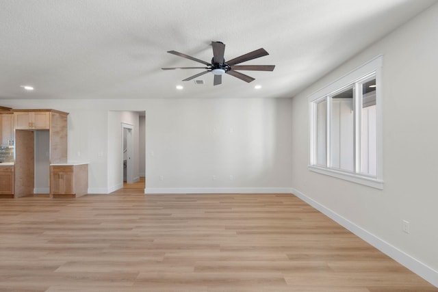 interior space featuring baseboards, a textured ceiling, recessed lighting, and light wood-style floors