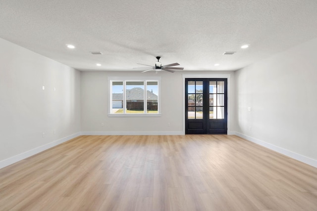 spare room featuring light wood-type flooring, french doors, and visible vents