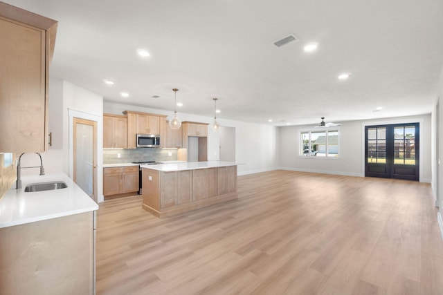 kitchen featuring tasteful backsplash, visible vents, light brown cabinetry, appliances with stainless steel finishes, and a sink