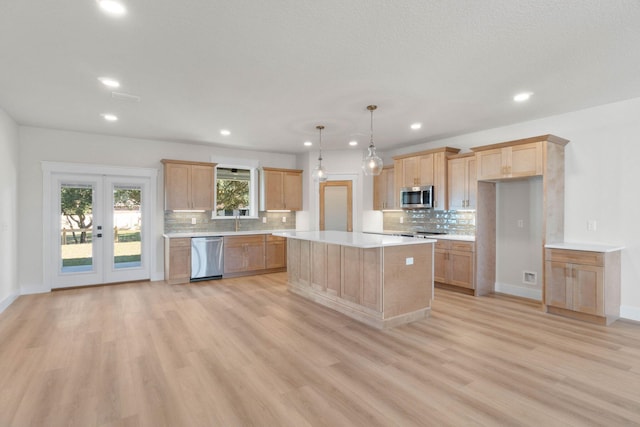 kitchen with light wood finished floors, light countertops, light brown cabinetry, appliances with stainless steel finishes, and a kitchen island