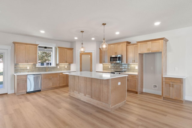 kitchen featuring a kitchen island, light countertops, appliances with stainless steel finishes, light brown cabinetry, and light wood finished floors