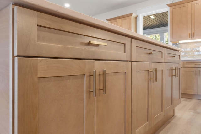 room details with light wood-style flooring, light brown cabinets, and backsplash