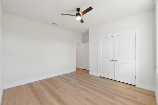 unfurnished bedroom with light wood finished floors, visible vents, baseboards, ceiling fan, and a closet