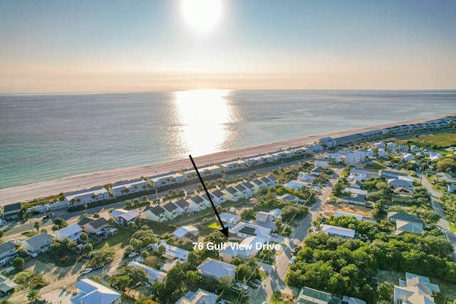 aerial view at dusk with a beach view, a water view, and a residential view