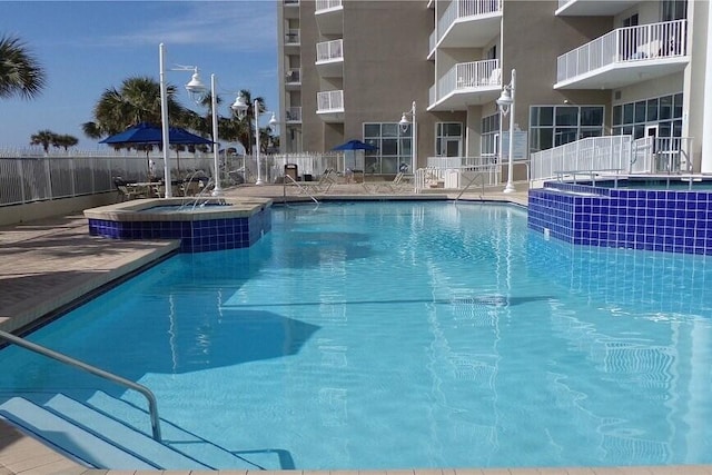 pool with fence and a hot tub