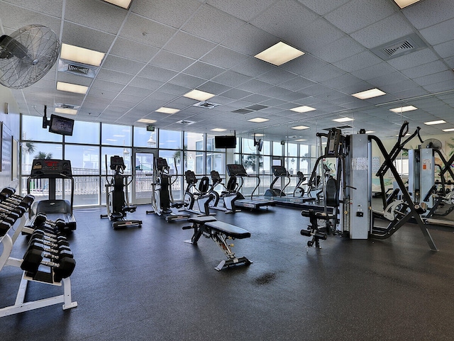 workout area with a paneled ceiling, visible vents, and plenty of natural light