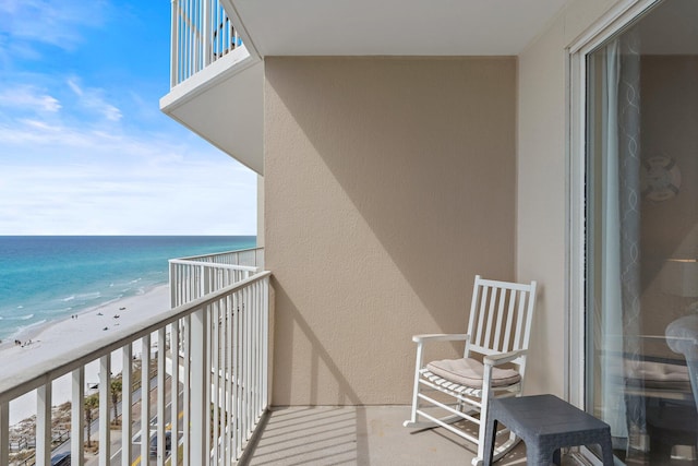 balcony featuring a view of the beach and a water view