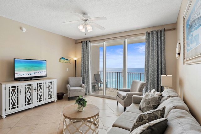 tiled living area featuring a ceiling fan, a water view, and a textured ceiling