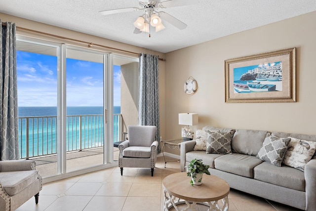 living room with a water view, light tile patterned floors, ceiling fan, and a textured ceiling