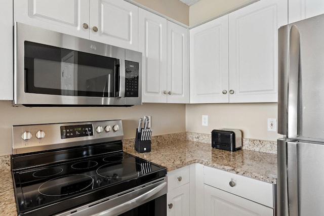 kitchen with appliances with stainless steel finishes, white cabinets, and light stone counters