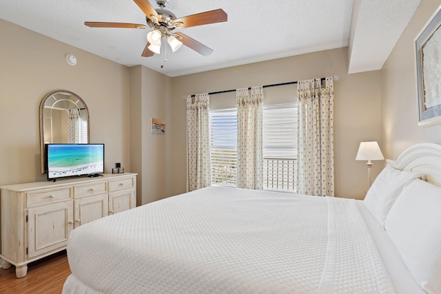 bedroom featuring ceiling fan, a textured ceiling, and light wood-style flooring