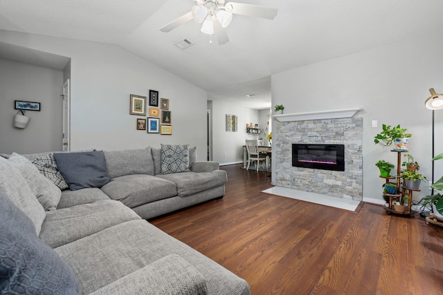 living area featuring visible vents, a ceiling fan, wood finished floors, a fireplace, and vaulted ceiling