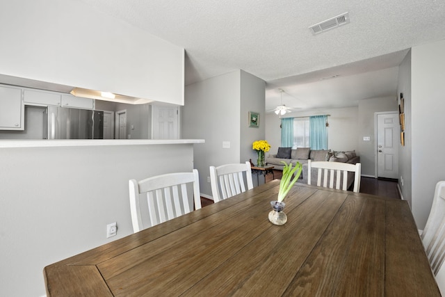 unfurnished dining area featuring visible vents, a textured ceiling, and a ceiling fan