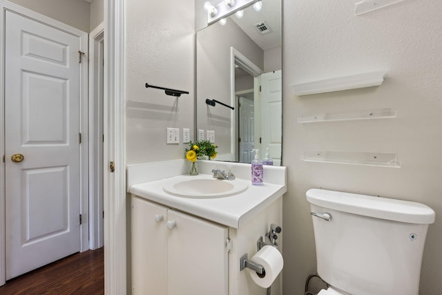 bathroom featuring visible vents, toilet, wood finished floors, and vanity