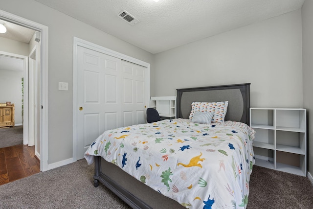 carpeted bedroom with baseboards, visible vents, a closet, and a textured ceiling