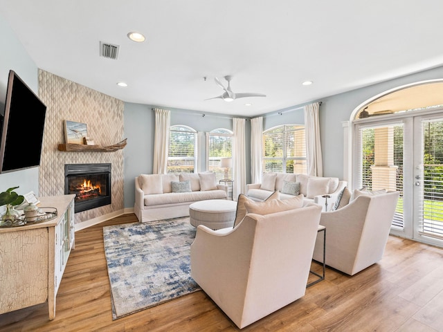 living room with french doors, a fireplace, recessed lighting, visible vents, and light wood-style flooring