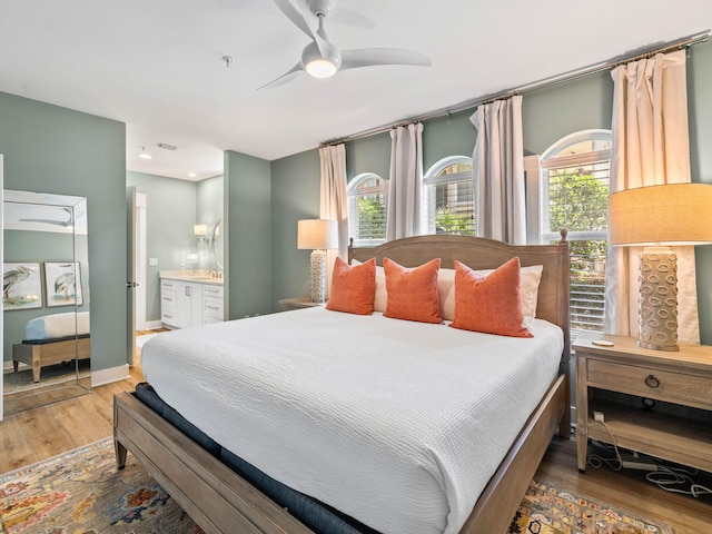 bedroom featuring a ceiling fan, baseboards, ensuite bath, and wood finished floors