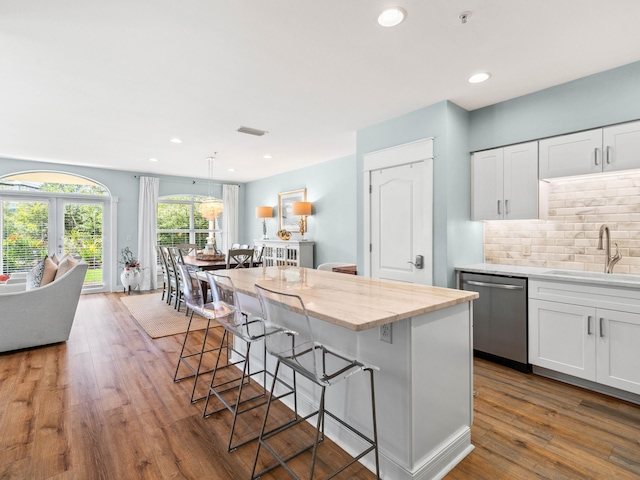 kitchen with a breakfast bar area, tasteful backsplash, white cabinetry, a sink, and dishwasher