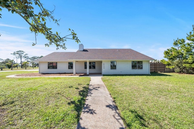 ranch-style home with brick siding, fence, a chimney, and a front lawn