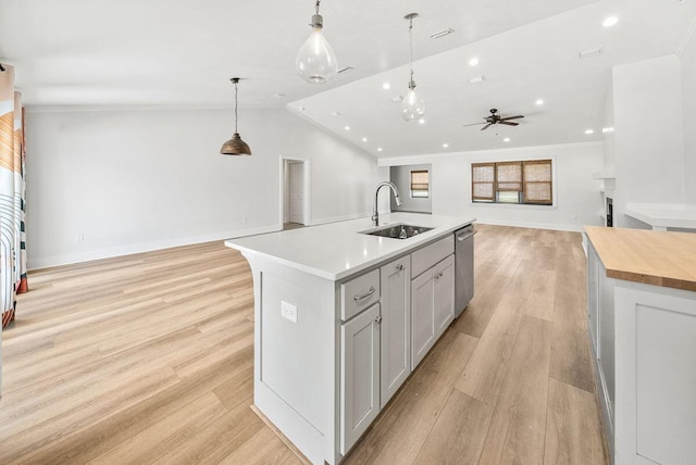 kitchen with open floor plan, light wood-style flooring, a sink, and a kitchen island with sink