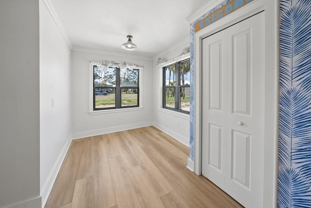 interior space featuring ornamental molding, light wood-type flooring, and baseboards