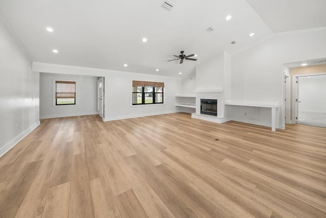 unfurnished living room with visible vents, a fireplace with raised hearth, lofted ceiling, crown molding, and light wood-type flooring