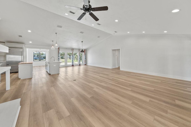 unfurnished living room with lofted ceiling, a sink, visible vents, light wood-style floors, and french doors