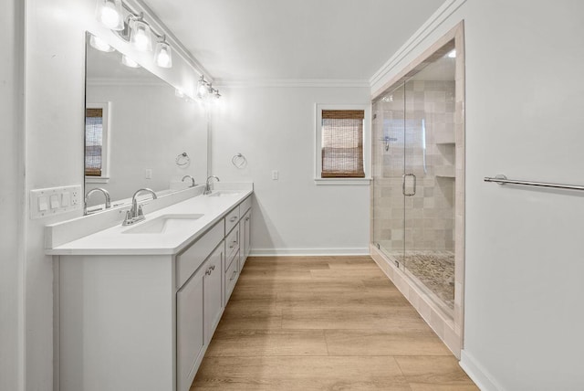 bathroom with wood finished floors, a stall shower, a sink, and crown molding