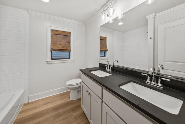 bathroom with ornamental molding, a sink, baseboards, and wood finished floors