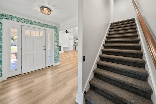 foyer entrance featuring ornamental molding, light wood-type flooring, baseboards, and stairs