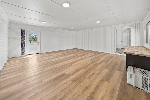 unfurnished room featuring brick wall and light wood-type flooring