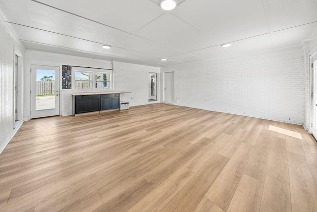 unfurnished living room featuring light wood-type flooring and brick wall