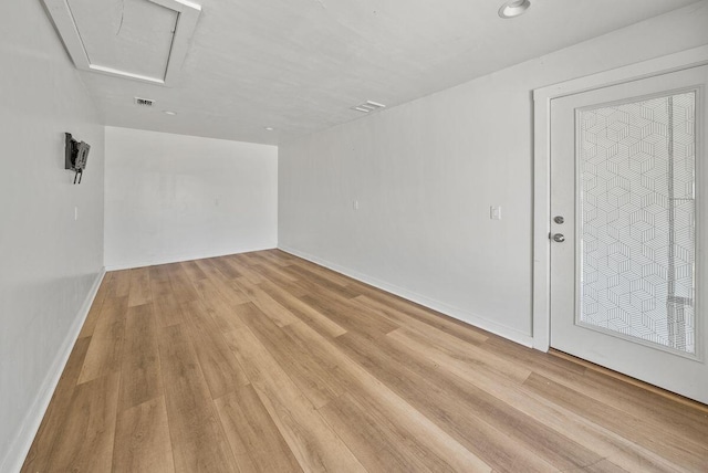 spare room featuring light wood-style floors, visible vents, and baseboards