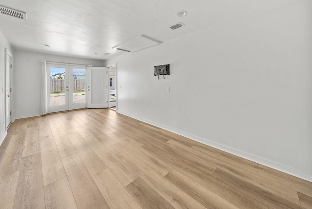 empty room with attic access, french doors, visible vents, and light wood-style flooring