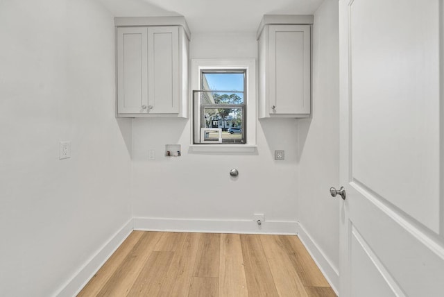 laundry area with cabinet space, baseboards, washer hookup, and light wood finished floors