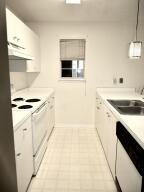 kitchen featuring light countertops, hanging light fixtures, a sink, white appliances, and under cabinet range hood