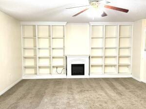 unfurnished living room featuring a ceiling fan, a fireplace, baseboards, and carpet flooring