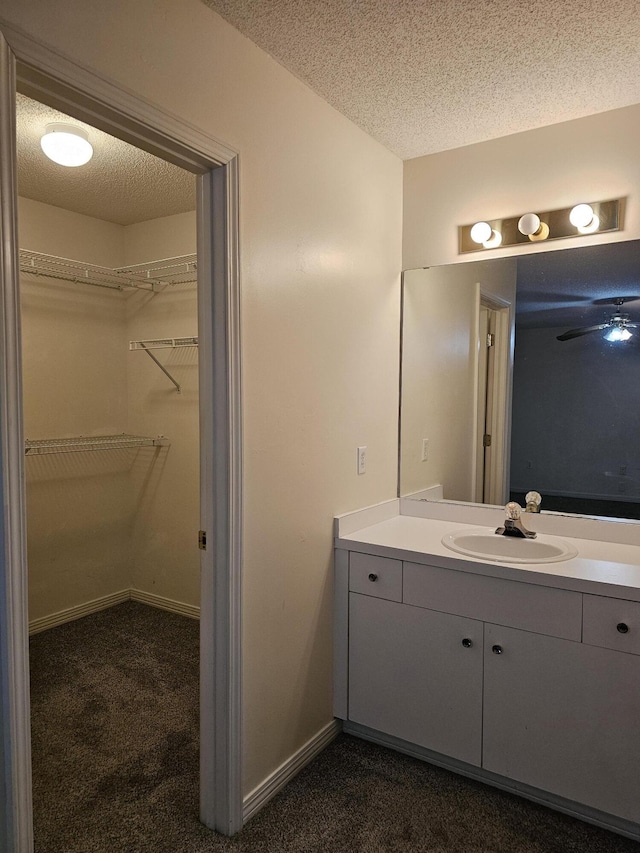 946 Ashley Ln Unit C, Fort Walton Beach, FL 32547 - bathroom featuring vanity, a textured ceiling, a walk in closet, and baseboards