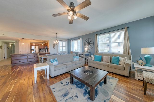 living room featuring ceiling fan with notable chandelier and wood finished floors